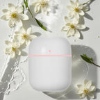 White electronic device with a pink light surrounded by white flowers on a light background