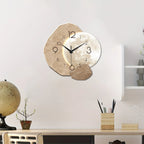 Wooden wall clock on a white wall with a desk and decorative items below.