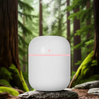 White humidifier with a pink light on a rock in a forest setting