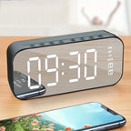 Digital clock with LED display on a wooden surface, next to a smartphone.