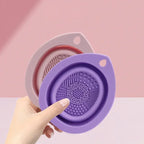 Purple silicone strainer held by a hand against a pink background