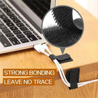 Cable management strap holding a cable to a wooden surface with a laptop in the background.